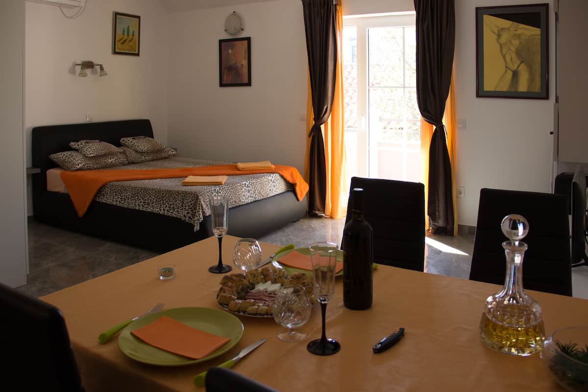 A hotel room with a bed, a dining table with plates, glasses, and a bottle.