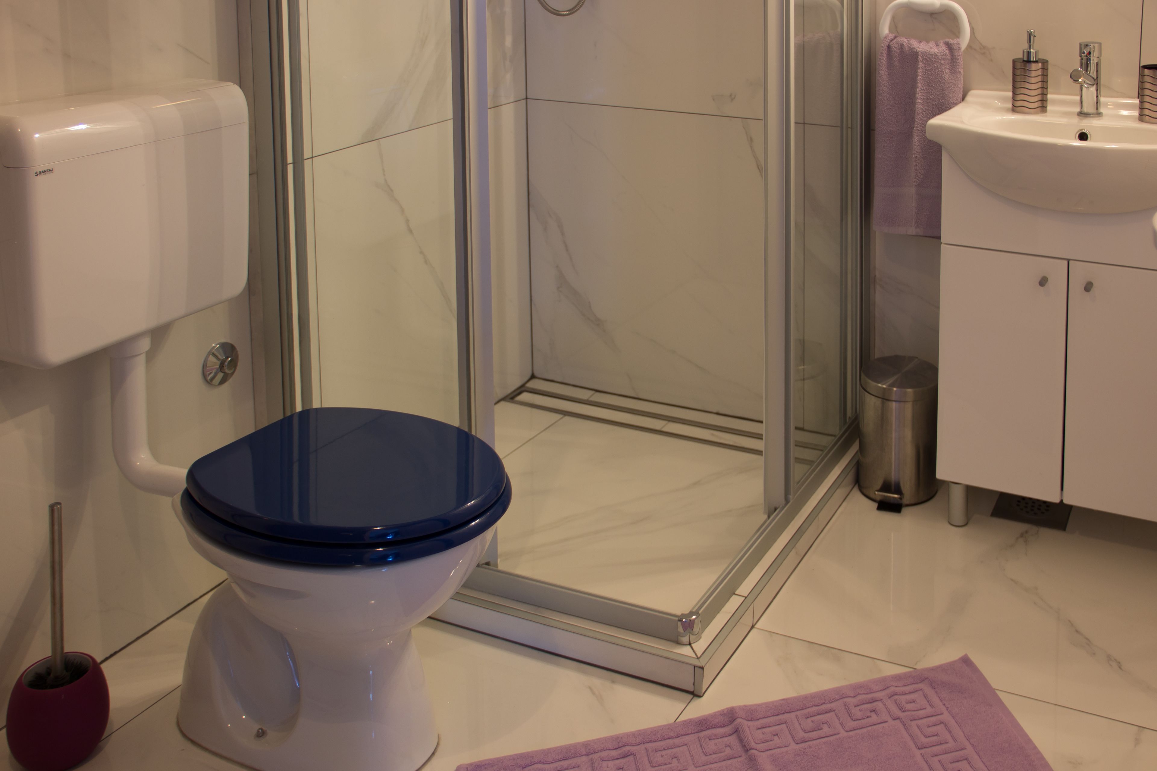 Ein Badezimmer mit Toilette, Dusche, Waschbecken und einem Marmorboden.
