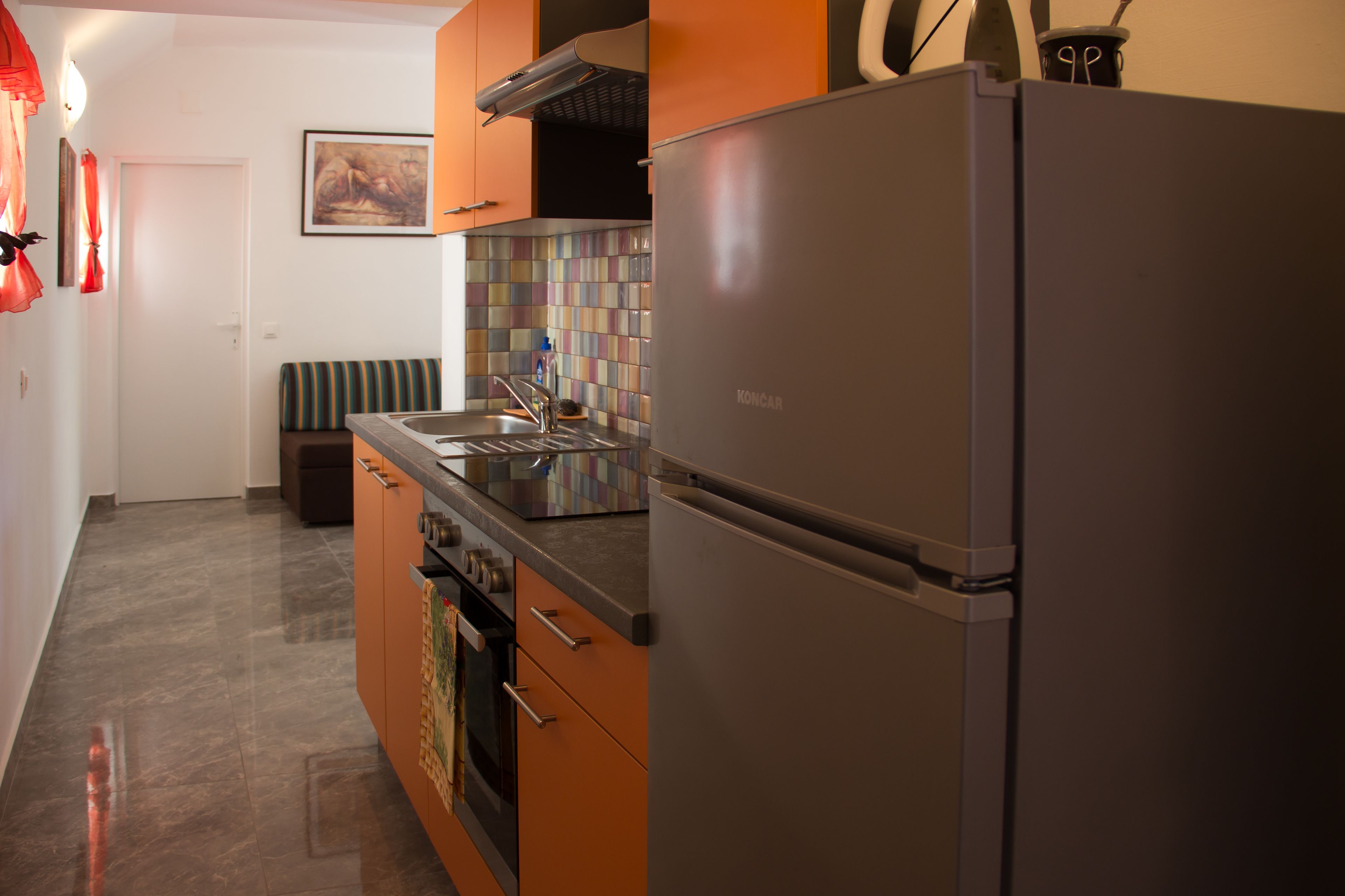 A kitchen with a stainless steel refrigerator, a tiled backsplash, and a sink.