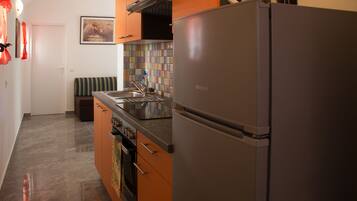 A kitchen with a stainless steel refrigerator, a tiled backsplash, and a sink.
