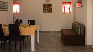 A dining area with a table set for four, a sofa, and a painting on the wall.