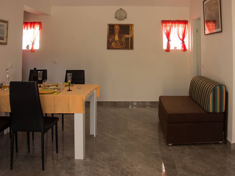 Un comedor con una mesa preparada para cuatro personas, un sofá y un cuadro en la pared.