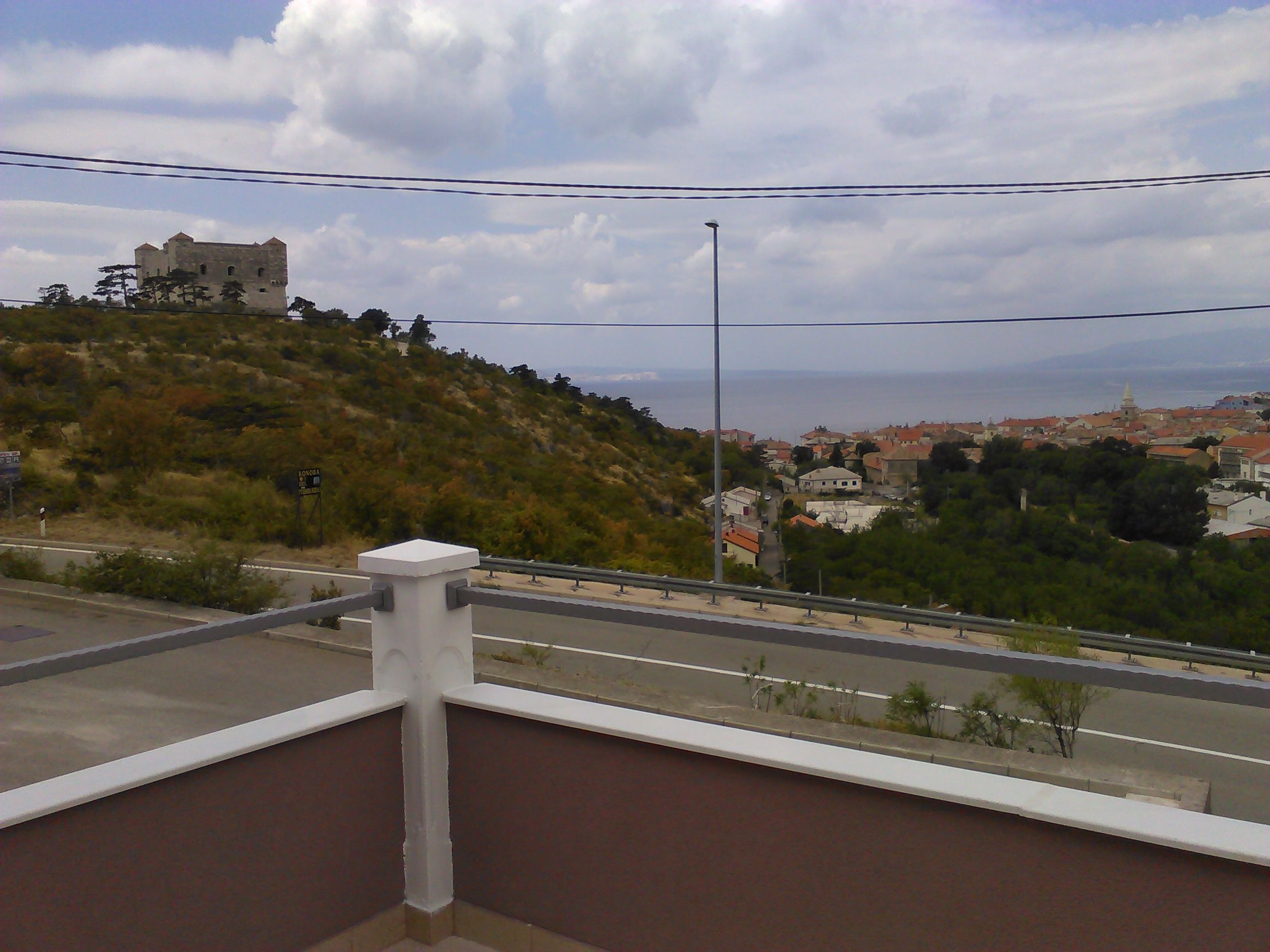 A view of a hilltop castle overlooking a coastal town.