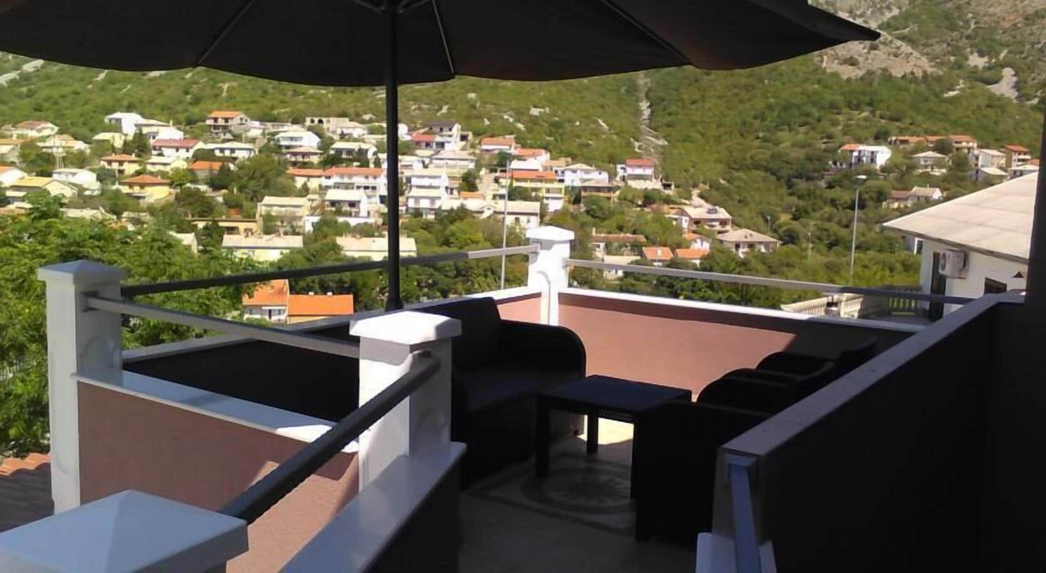 A balcony with outdoor furniture and a view of a hillside town.