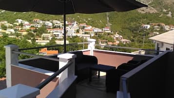 A balcony with outdoor furniture and a view of a hillside town.