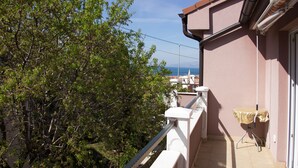A balcony with a view of trees and a distant cityscape.