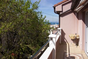 A balcony with a view of trees and a distant cityscape.