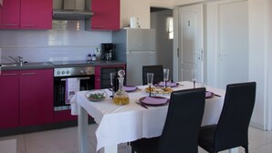 Una cocina moderna con armarios rosados, una mesa blanca dispuesta para comer y un refrigerador.