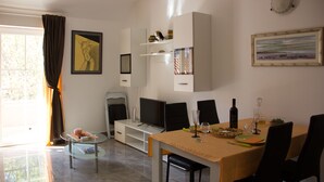 Un comedor con una mesa lista para dos personas, un televisor y un sofá.