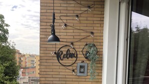 Ein Balkon mit weißem Tisch und Stühlen, einer hängenden Leuchte und einem Schild mit der Aufschrift 'Relax'.