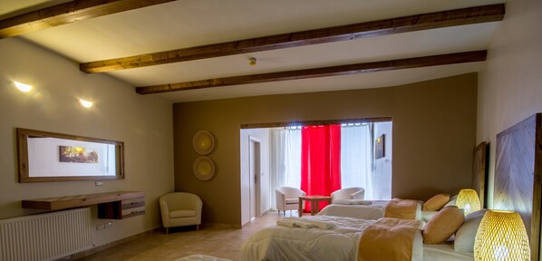 A hotel room with a bed, two chairs, a small table, and a red curtain.
