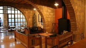A rustic interior with stone walls, wooden furniture, and a fireplace. - Dana Guest House (Dana)