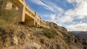 A multi-story hotel with balconies, situated on a hillside with a clear sky. - Dana Guest House (Dana)