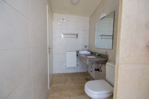A bathroom with a toilet, sink, and mirror. - Dana Guest House (Dana)