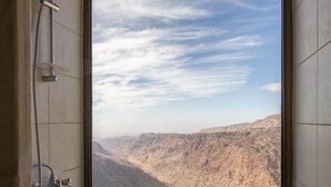 A bathroom with a shower, a window, and a view of a mountainous landscape. - Dana Guest House (Dana)