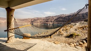 Un hamac suspendu sous une structure, avec vue sur un lac et des montagnes.