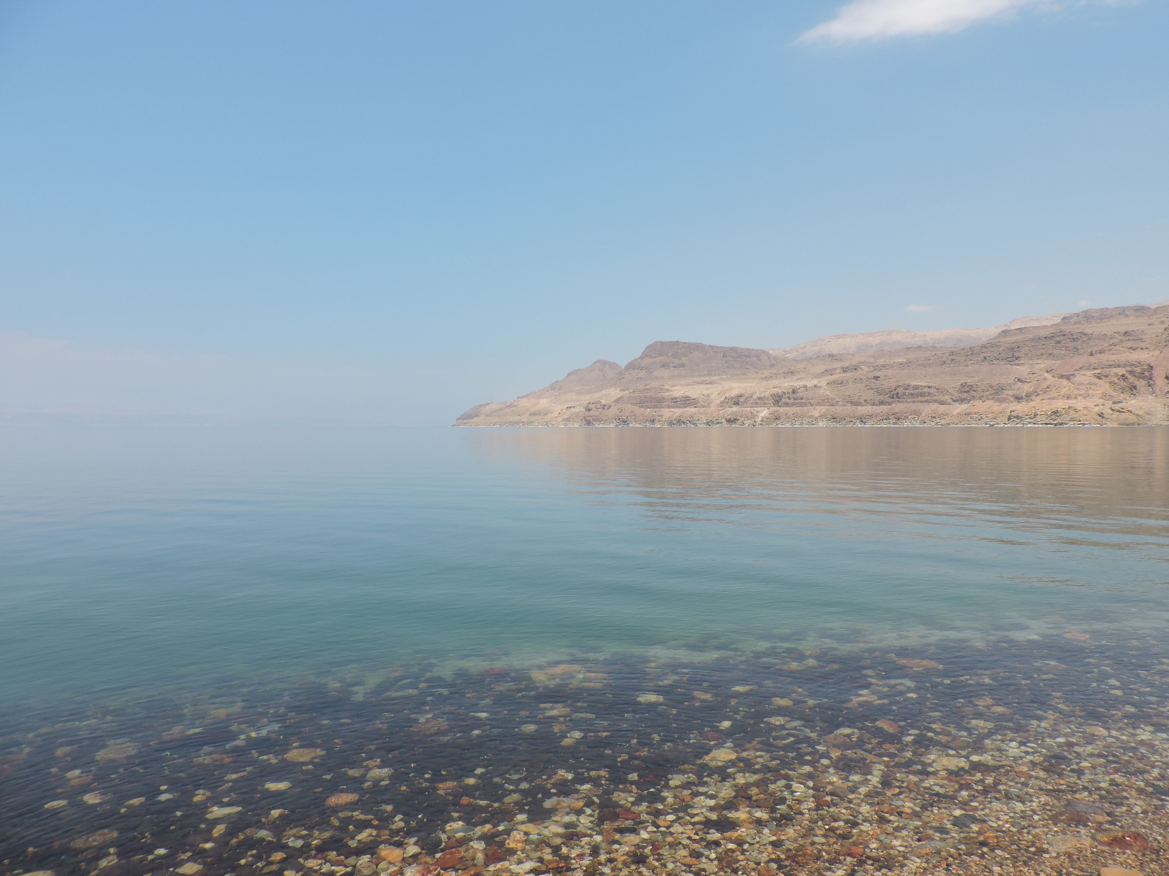 Un lac paisible aux eaux claires, où l’on peut distinguer les galets et les rochers au fond.