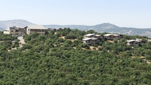 A hillside property with modern buildings, dense greenery, and a mountainous backdrop. - Ajloun cabins (Ajloun)