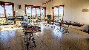 A spacious kitchen with large windows, a central island with a large pan, and various kitchen appliances. - Ajloun cabins (Ajloun)