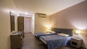 Et hotelværelse med to senge, en kommode, et spejl, en aircondition og en sengebordlampe.