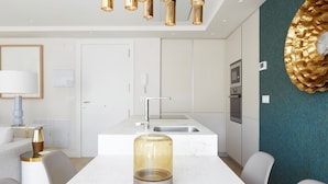 Una cocina moderna con encimera blanca, electrodomésticos de acero inoxidable y un adorno dorado en la pared.