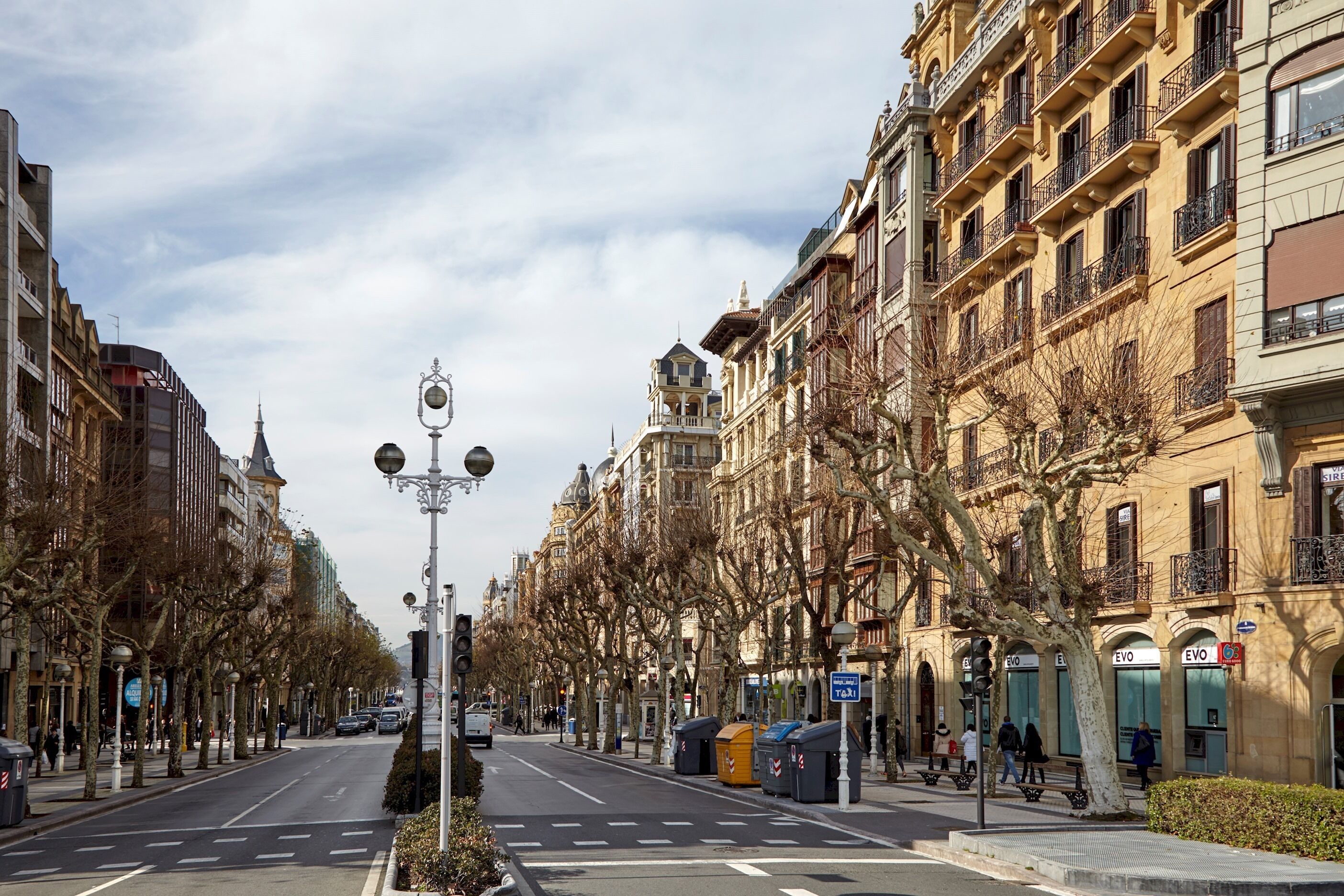 A street lined with historic buildings, a clear sky, and a few pedestrians.