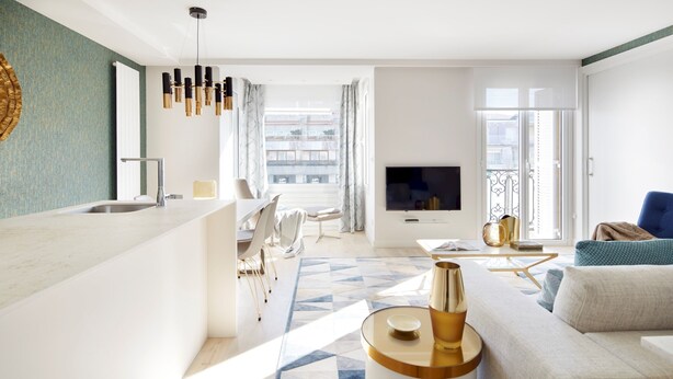 Una sala de estar moderna con sofá, televisor y comedor con mesa y sillas.