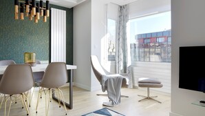 Una sala de estar moderna con comedor, un ventanal con cortinas, un televisor de pantalla plana y un diseño de silla único.