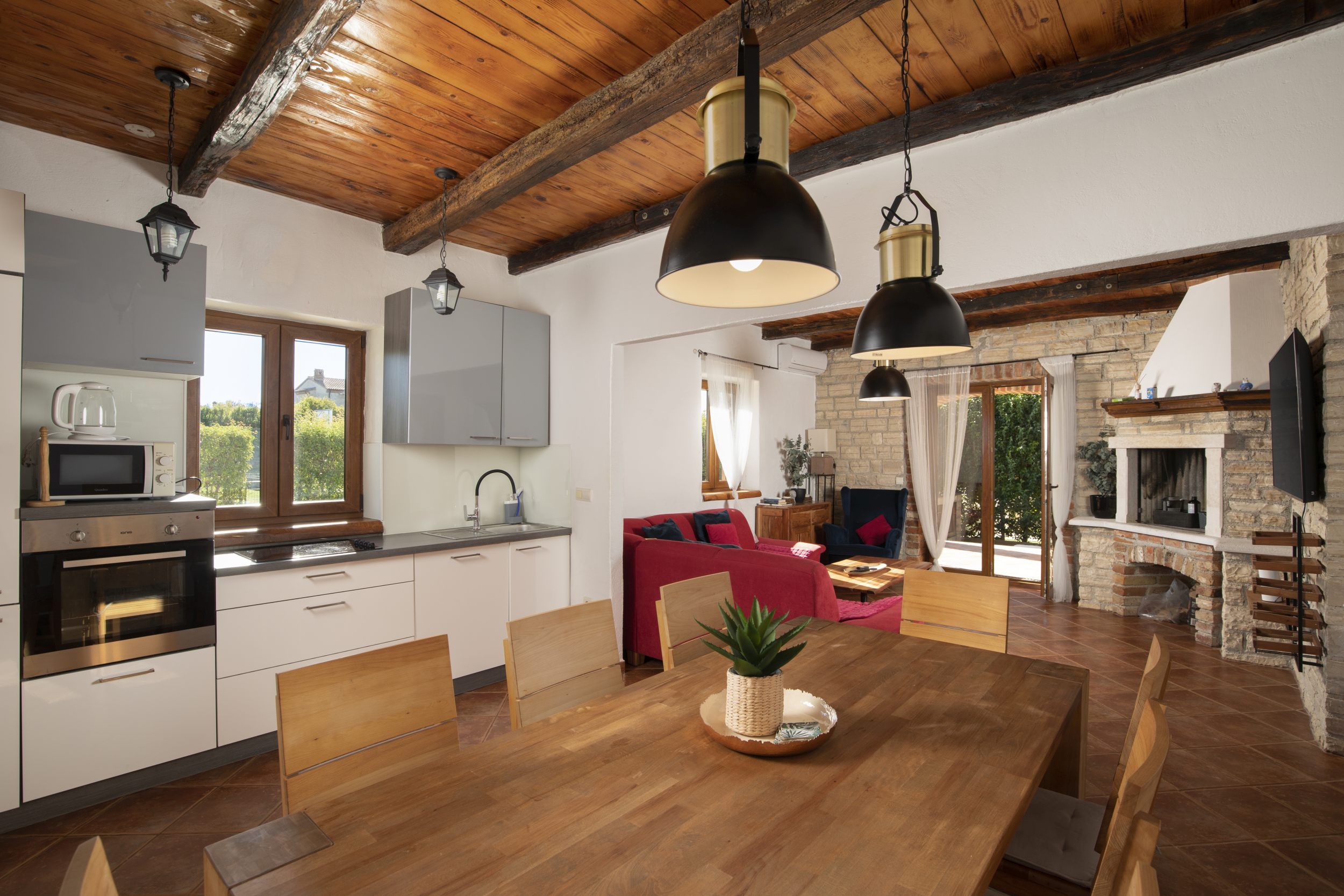 Een moderne keuken met een eethoek, houten balken en een stenen open haard.