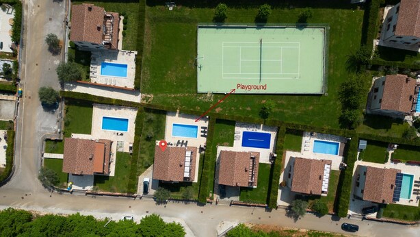 Une vue aérienne d’un quartier résidentiel composé de plusieurs maisons, chacune dotée d’une piscine et d’un court de tennis.