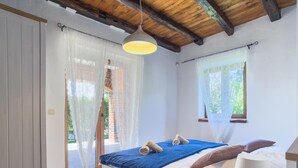 A bedroom with a bed, a bedside table, a lamp, and a window.