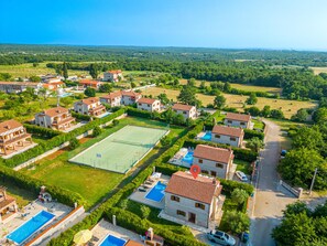 Een woonwijk met huizen, een tennisbaan en zwembaden.