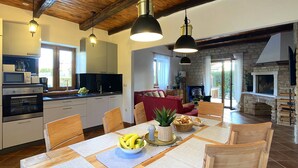 A modern kitchen with built-in appliances, a dining area with a table set for four, and a stone fireplace.