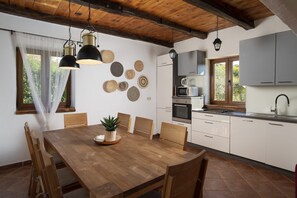 Une cuisine moderne avec des meubles blancs, une table à manger en bois et divers objets décoratifs accrochés au mur.