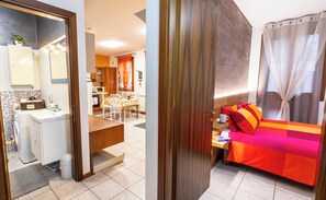 A modern hotel room with a dining area, a kitchen, and a bathroom.