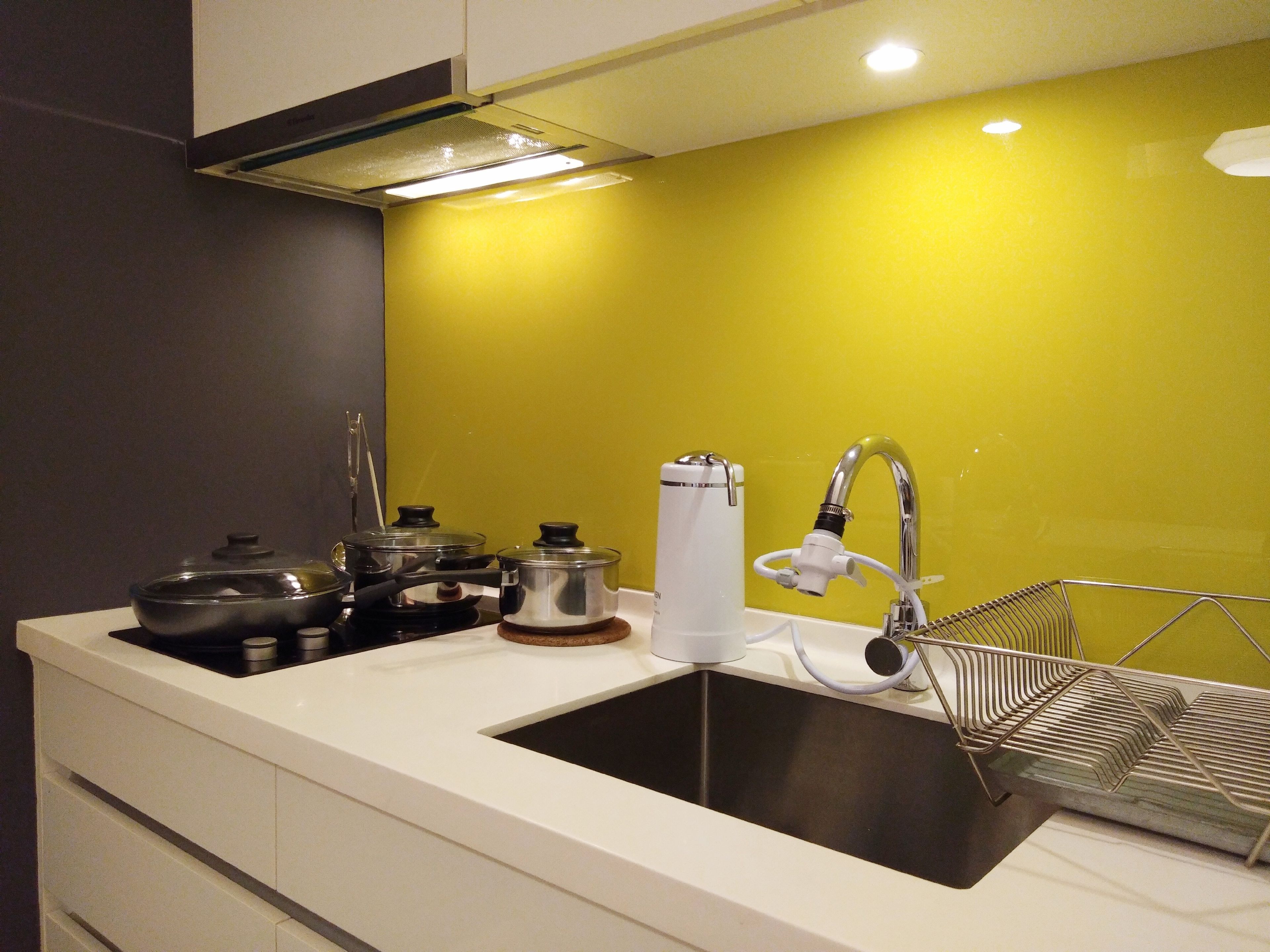Una cocina con un lavamanos, estufa y ollas.