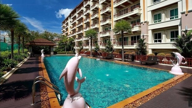 Un hotel con una piscina grande, varios balcones y palmeras.