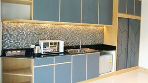Een moderne keuken met een magnetron, spoelbak en decoratieve spatwand.