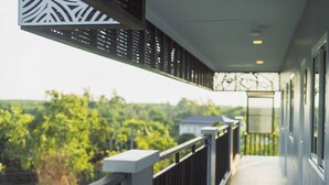 Een balkon met uitzicht op groen en een gebouw in de verte.