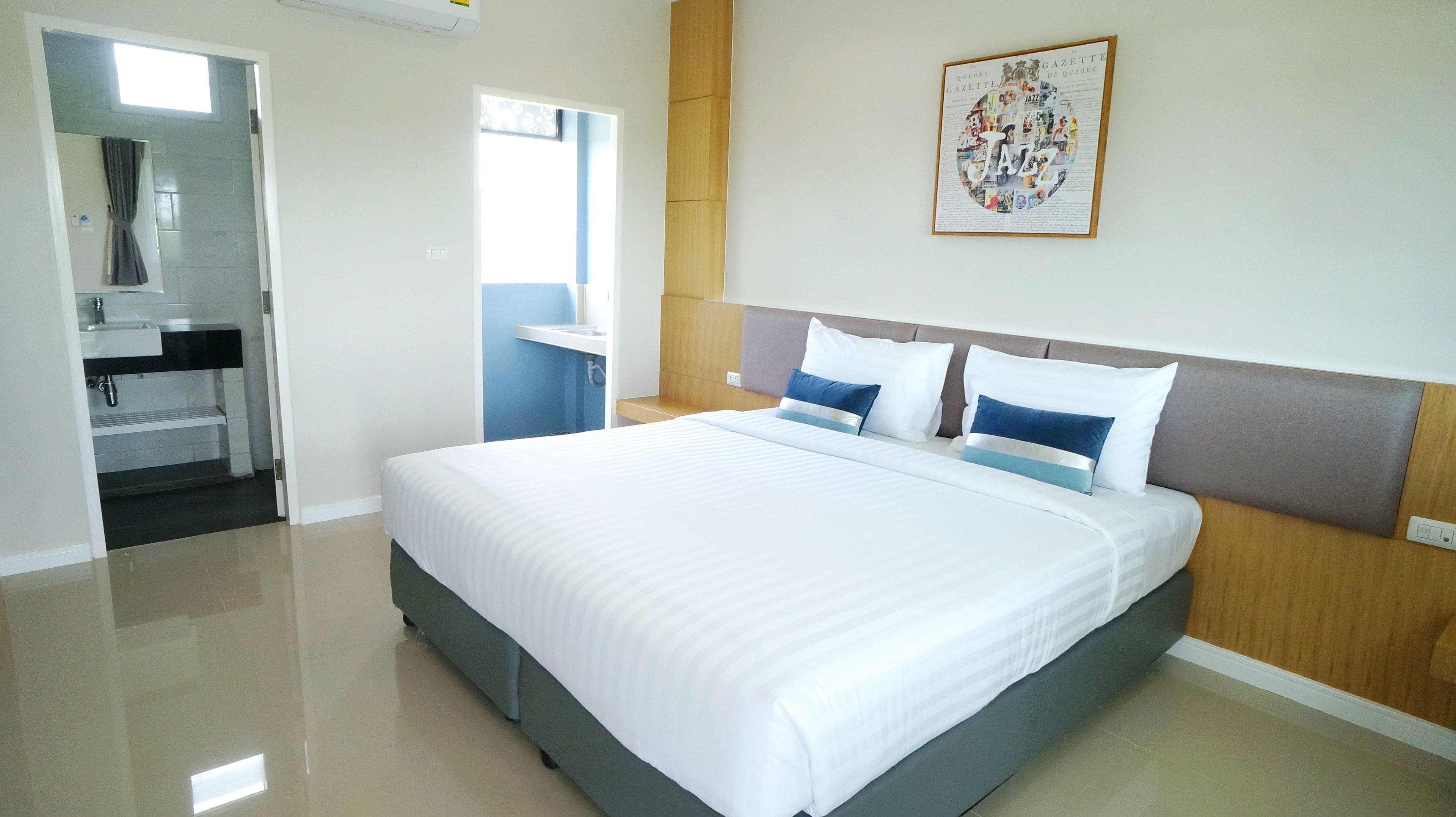 A hotel room with a large bed, a bedside table, a mirror, and a bathroom visible through an open door.