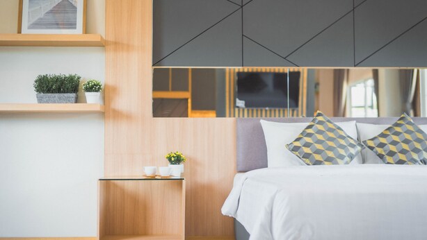 Een moderne slaapkamer met een bed, nachtkastjes en een aan de muur bevestigde televisie.
