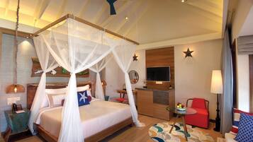 Un dormitorio amplio con cama con dosel, un escritorio, un sillón rojo y un televisor.