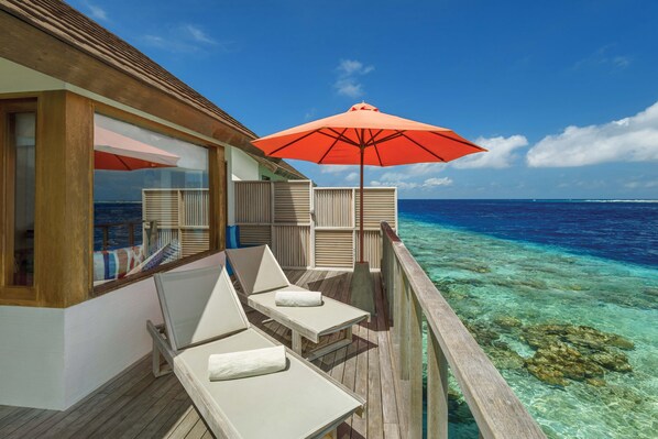 An overwater bungalows with wooden deck, white lounge chairs, and a red umbrella. - OBLU SELECT Sangeli - Premium All Inclusive with Free Transfers (Akirifushi)