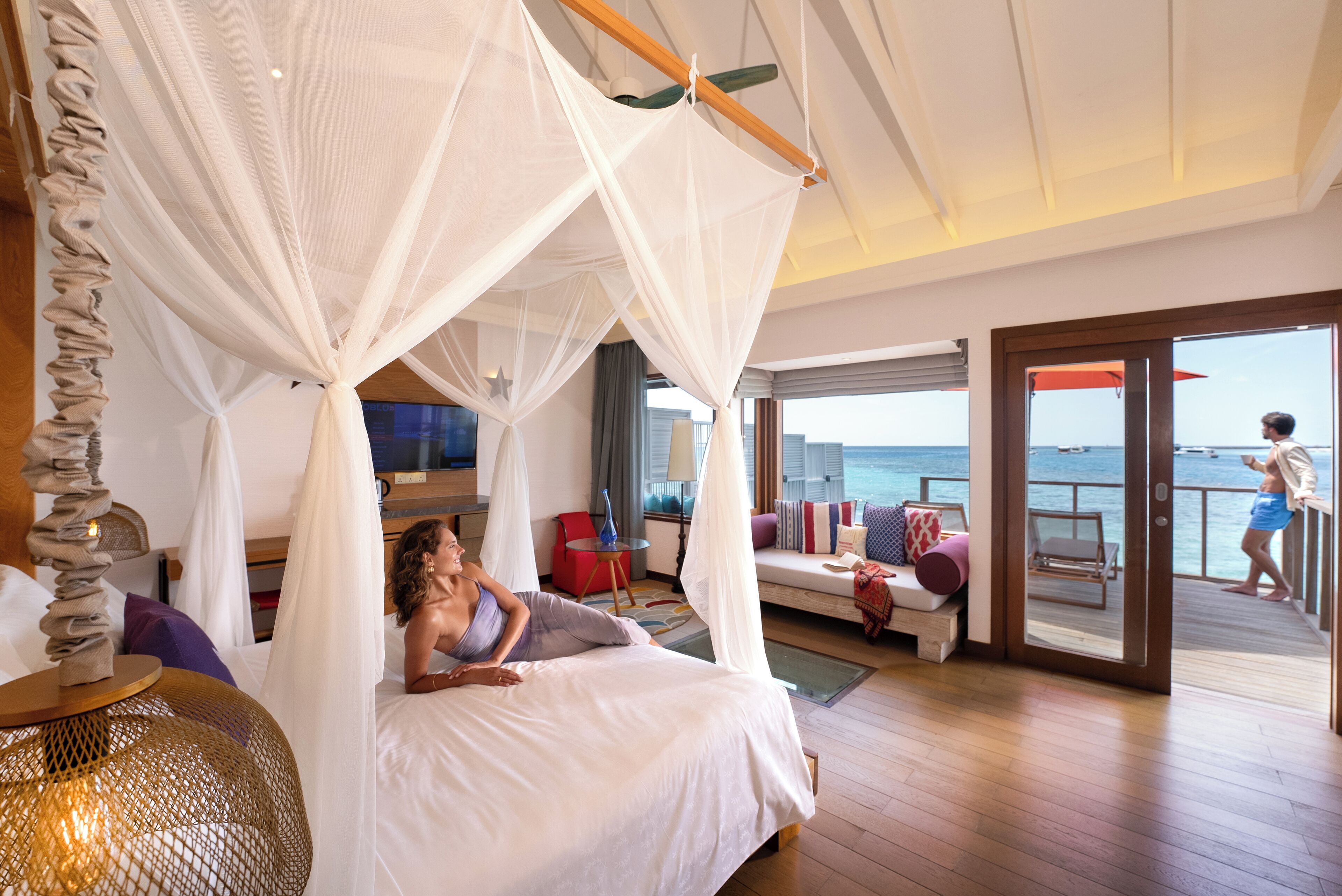 Un dormitorio con cama con dosel, televisión, sofá y vista al océano.