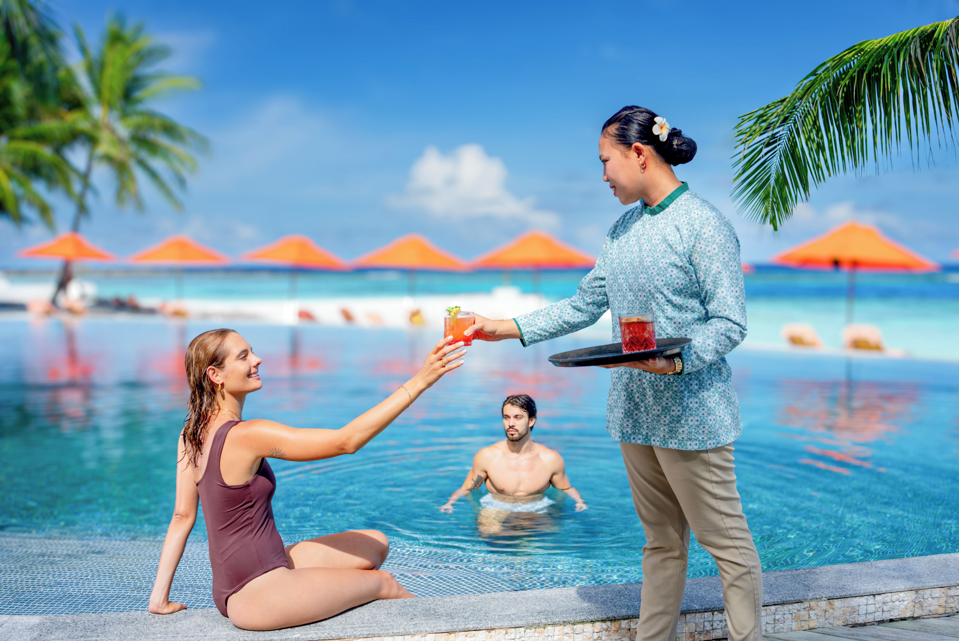 A poolside scene with a person serving drinks to another person.