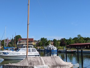 Ein Yachthafen mit vertäuten Booten, einer Fahnenmast und Gebäuden im Hintergrund.