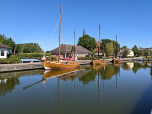 Ein ruhiger Wasserlauf mit angestaubten Holzbooten, umgeben von Häusern und Grünflächen.