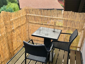 Eine Holzterrasse mit einem Tisch und zwei Stühlen.