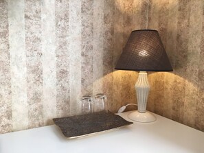 A white table with a textured lamp, a black tray, and three clear glasses.