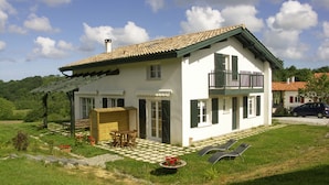 A white house with a tiled roof, a balcony, and a checkered patio. - Appartment Ihi-Toki, sunny garden apartment in a breathtaking location (Saint-Pée-sur-Nivelle)